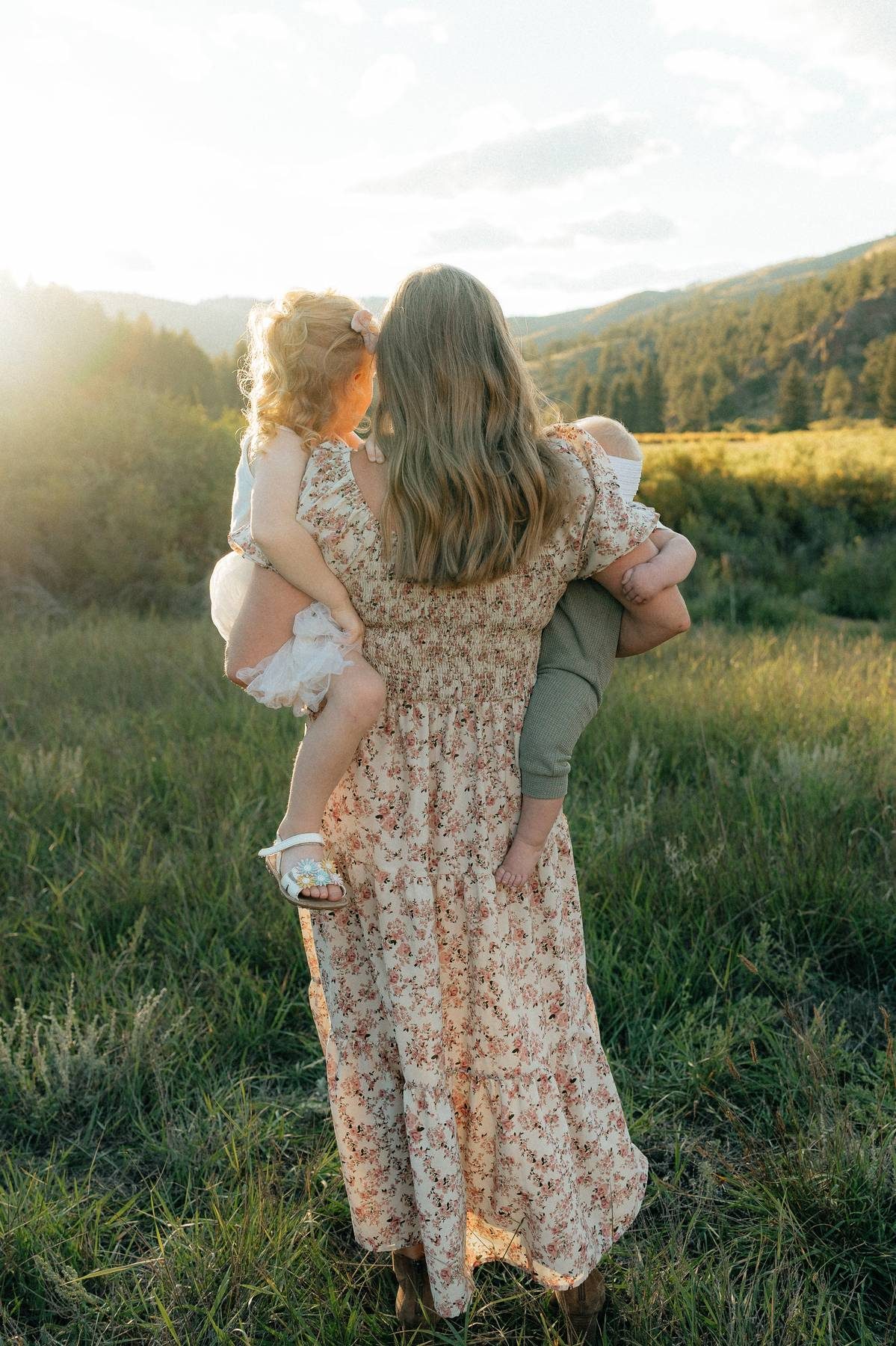 Ellen LeBleu carrying her two children through a sunlit meadow